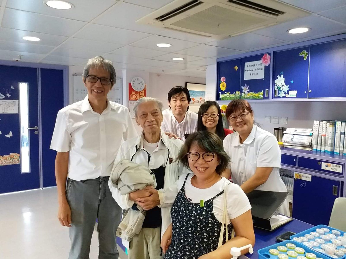 Vivian's father standing with family members and two nurses in the reception area of the nursing home, everyone smiling.