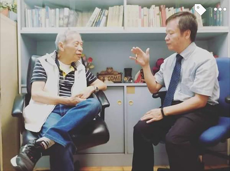 Vivian's father sitting and talking with a pastor in a small room lined with bookshelves.